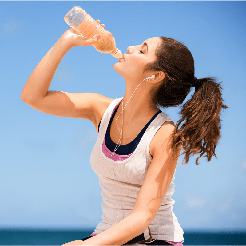 Woman drinking water outdoors with a clear blue sky background