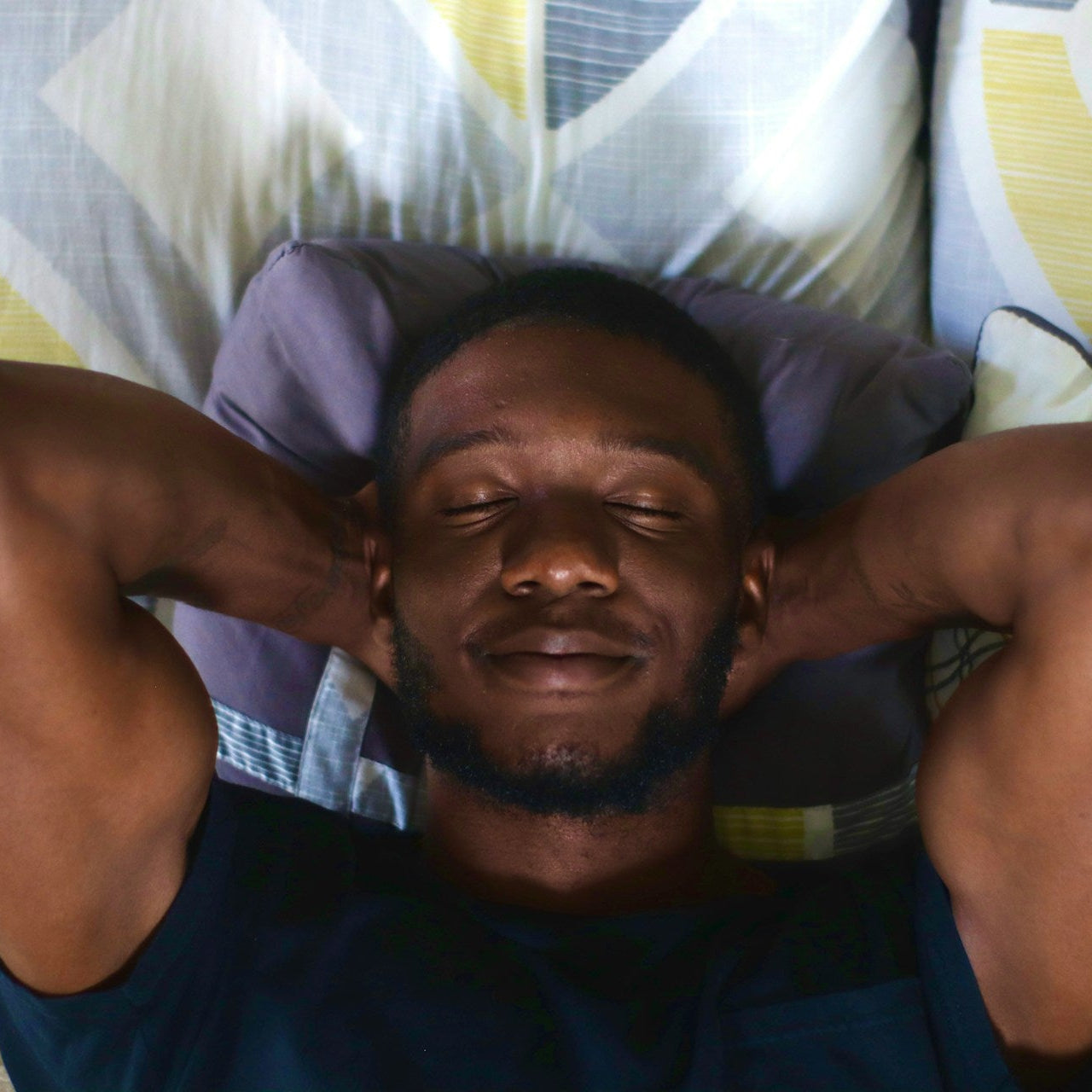 Man relaxing with eyes closed on a couch with patterned cushions
